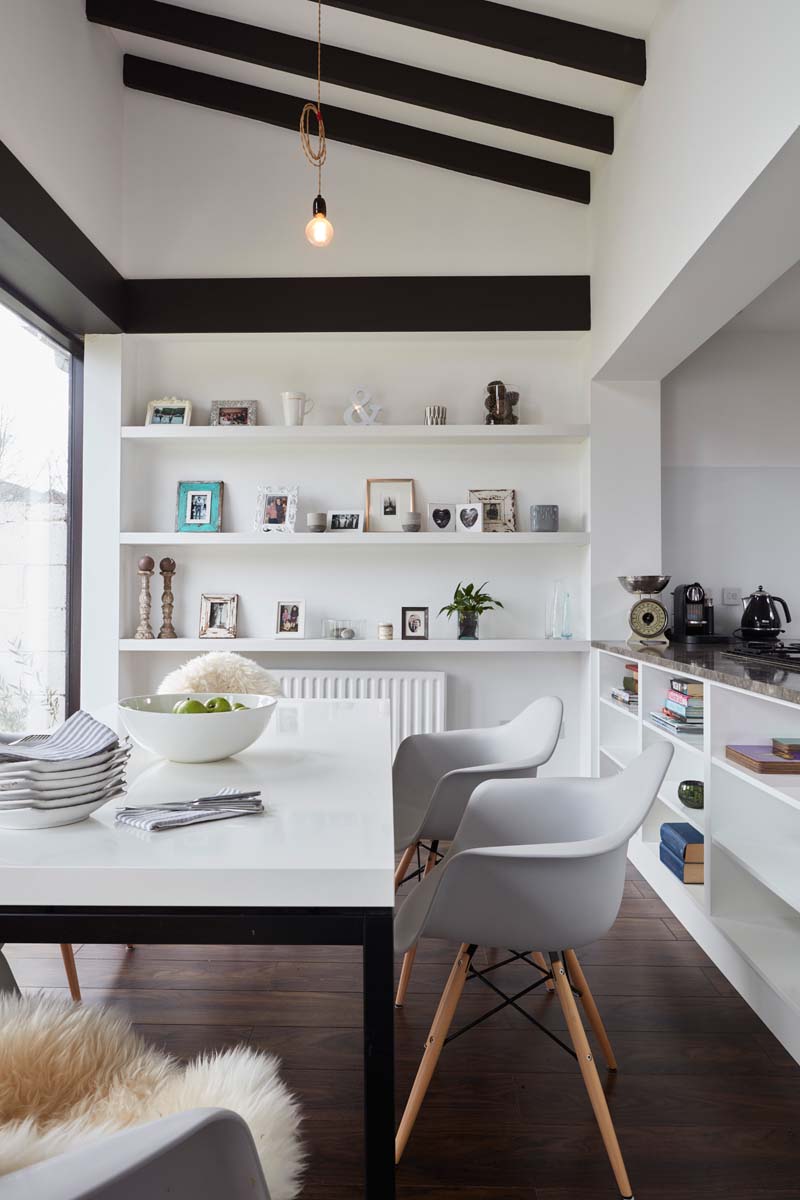 Open plan kitchen storage dining area timber beams table chairs open shelving bare bulb lighting