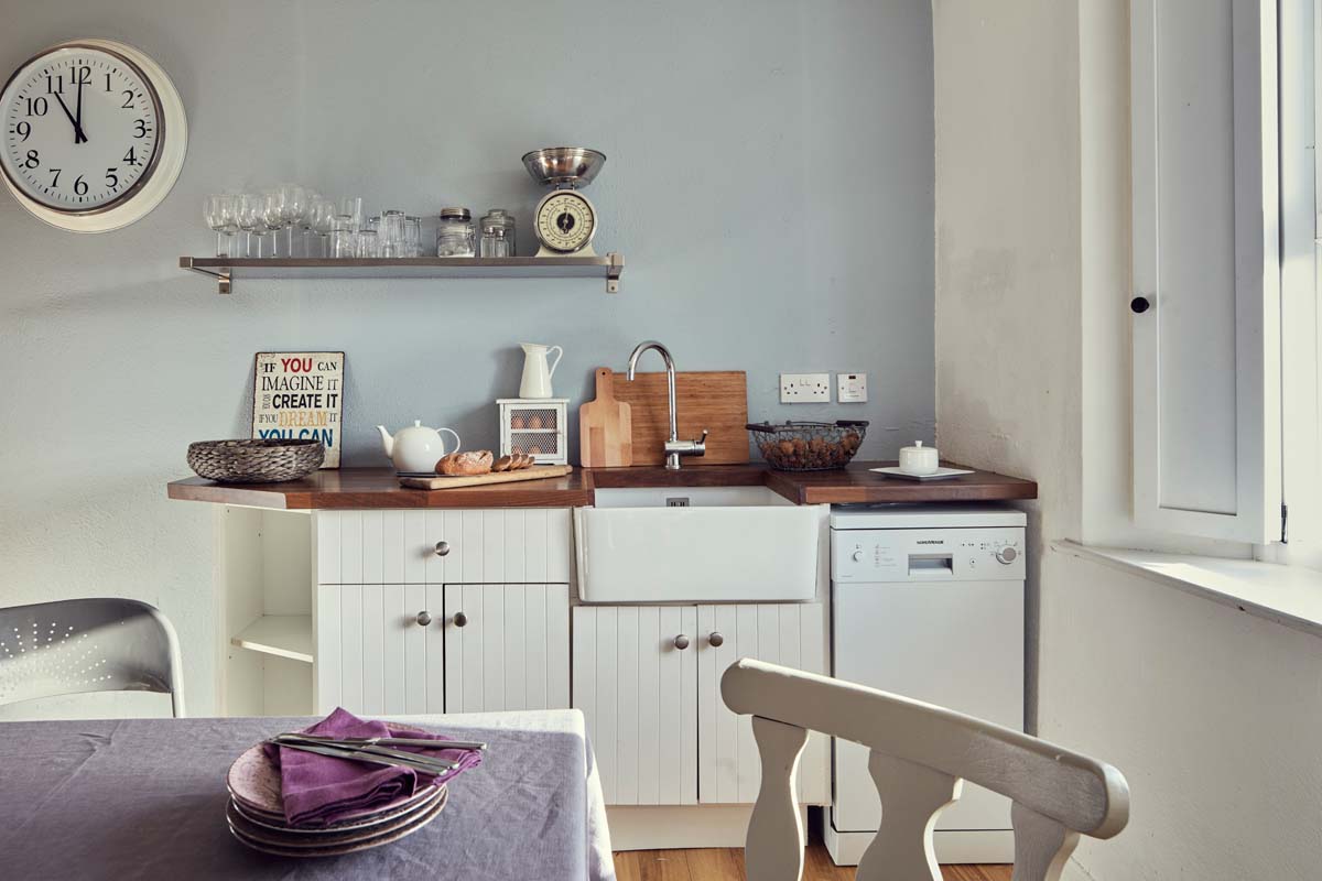 Kitchen area timber flooring table storage belfast sink shelving wall clock signage