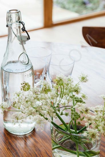 Timber dining table with a water bottle glassware flowers