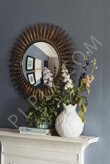Bedroom detail of mirror mantle piece plants books