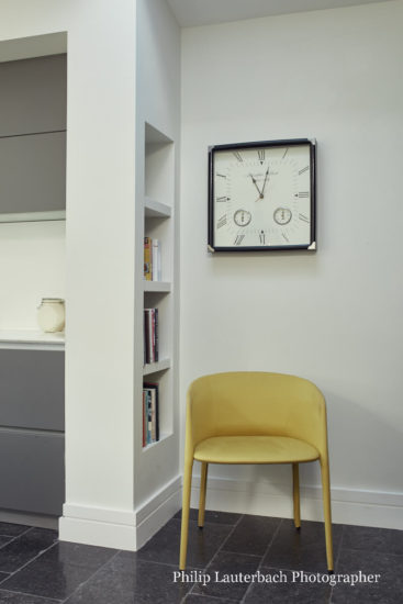 Open plan kitchen with stone fllooring storage chair wall clock
