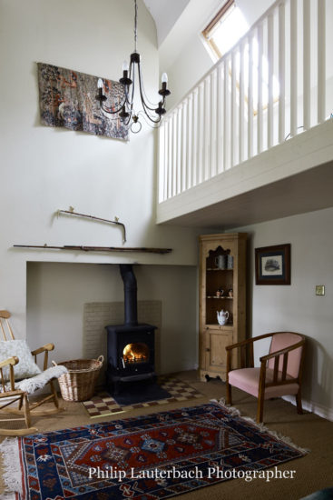 Hallway stairs open balcony wood burning stove rugchandelier dresser basket artwork